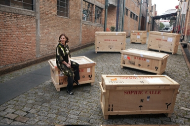 
	Artist Sophie Calle with boxes holding her pieces
	Photo: Everton Ballardin
